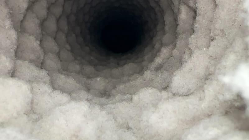 Looking straight down a dryer exhaust pipe with the walls furred over in packed lint