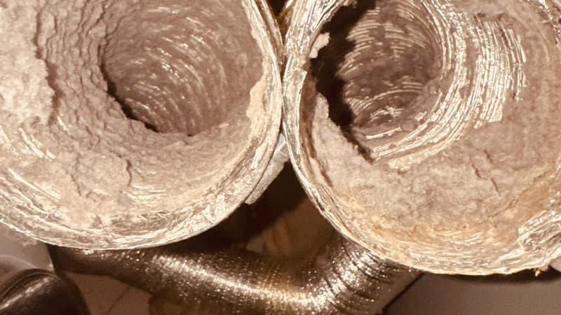 Two cut sections of dryer exhaust duct from an Oak Brook home, both packed solid with grey lint