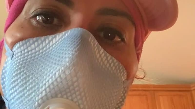 A Luxe Ducts team member in a pink company cap and a fitted respirator on a job site
